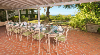 Cliff-side dining table set under cover with a sea view and terracotta floor at Mullins Mill, villa rental in Barbados