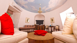 Round sitting room with a painted sky-dome ceiling and chandelier above cream sofas at Mullins Mill, Barbados