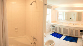 Bathroom with a tiled tub-shower and twin-basin vanity beneath a framed mirror at Mullins Mill, Barbados