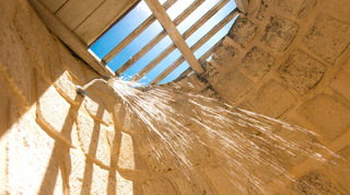 Rustic outdoor stone shower open to the sky under a timber-slatted roof at Mullins Mill, Barbados