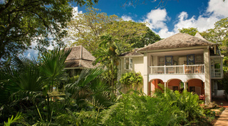 Arched verandah and hipped roofs framed by lush foliage at Mullins Mill, holiday villas in St. Peter, Barbados