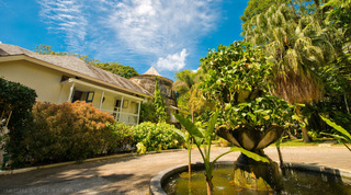 Circular drive with a stone planter fountain and the sugar mill tower beyond at Mullins Mill, Barbados