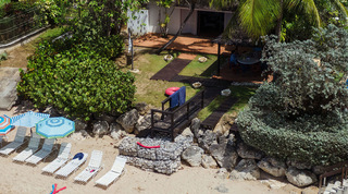 Aerial of the beach house garden meeting the sand with parasols and sun loungers at Mullins Mill, Barbados