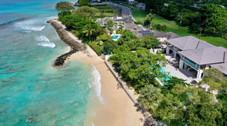Sandy beach and curving rock breakwater below One Beachlands villa on the West Coast, Barbados