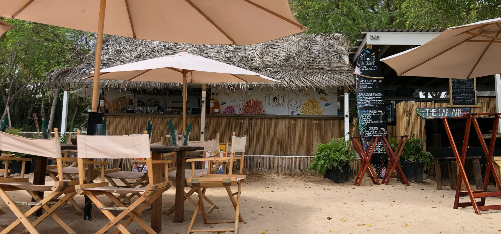 Tables in the sand looking toward the beach bar