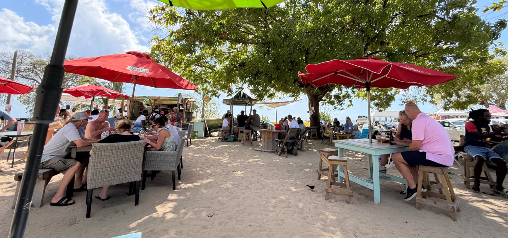 Caboose seating area and tables on the sand with the Caboose boat in the background