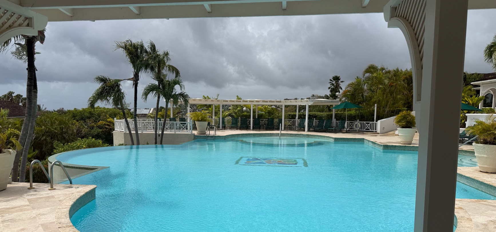 The large communal swimming pool at the Sugar Hill clubhouse, framed by palms, Barbados