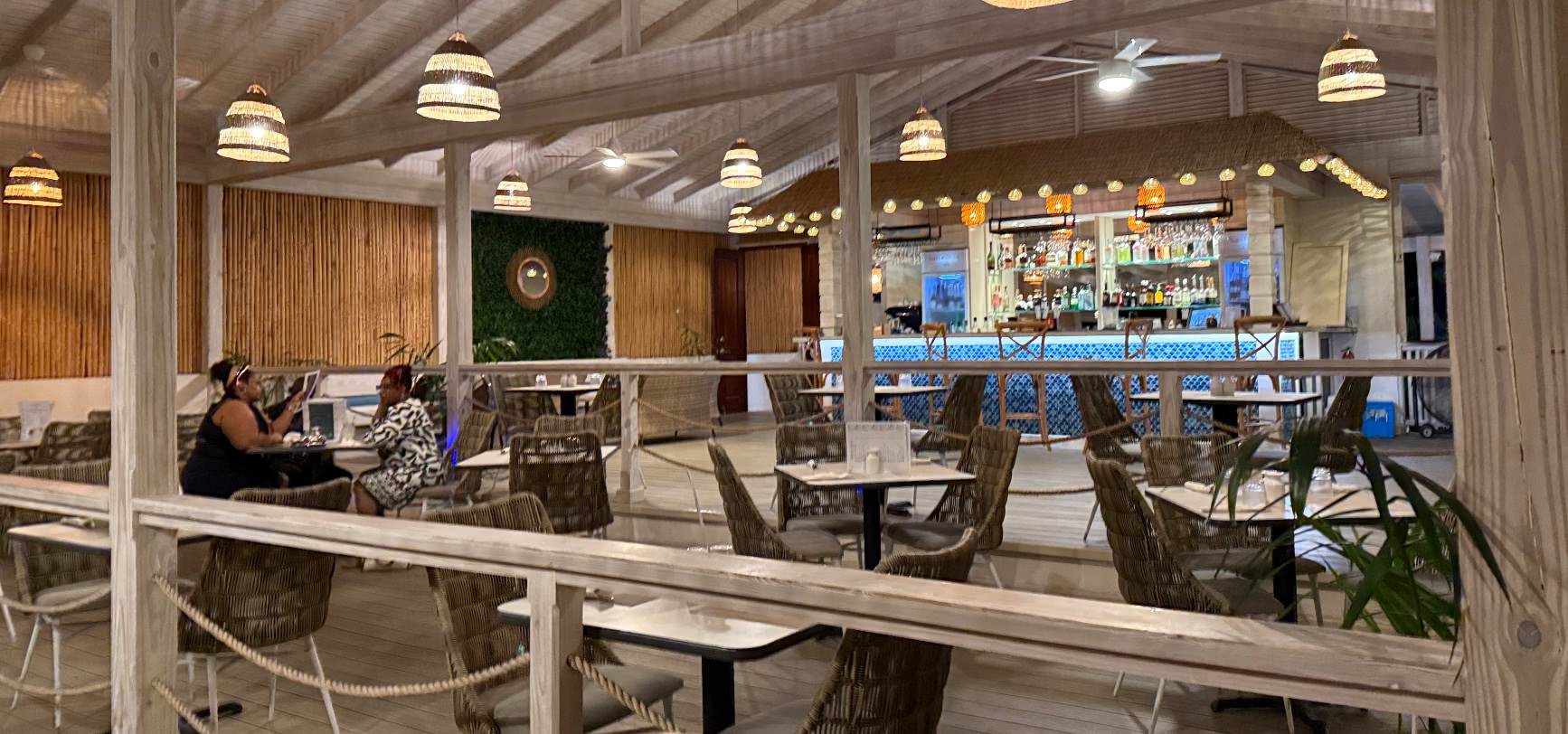 The open-air dining room with vaulted whitewashed timber ceiling, woven rattan pendant lights and tiered seating