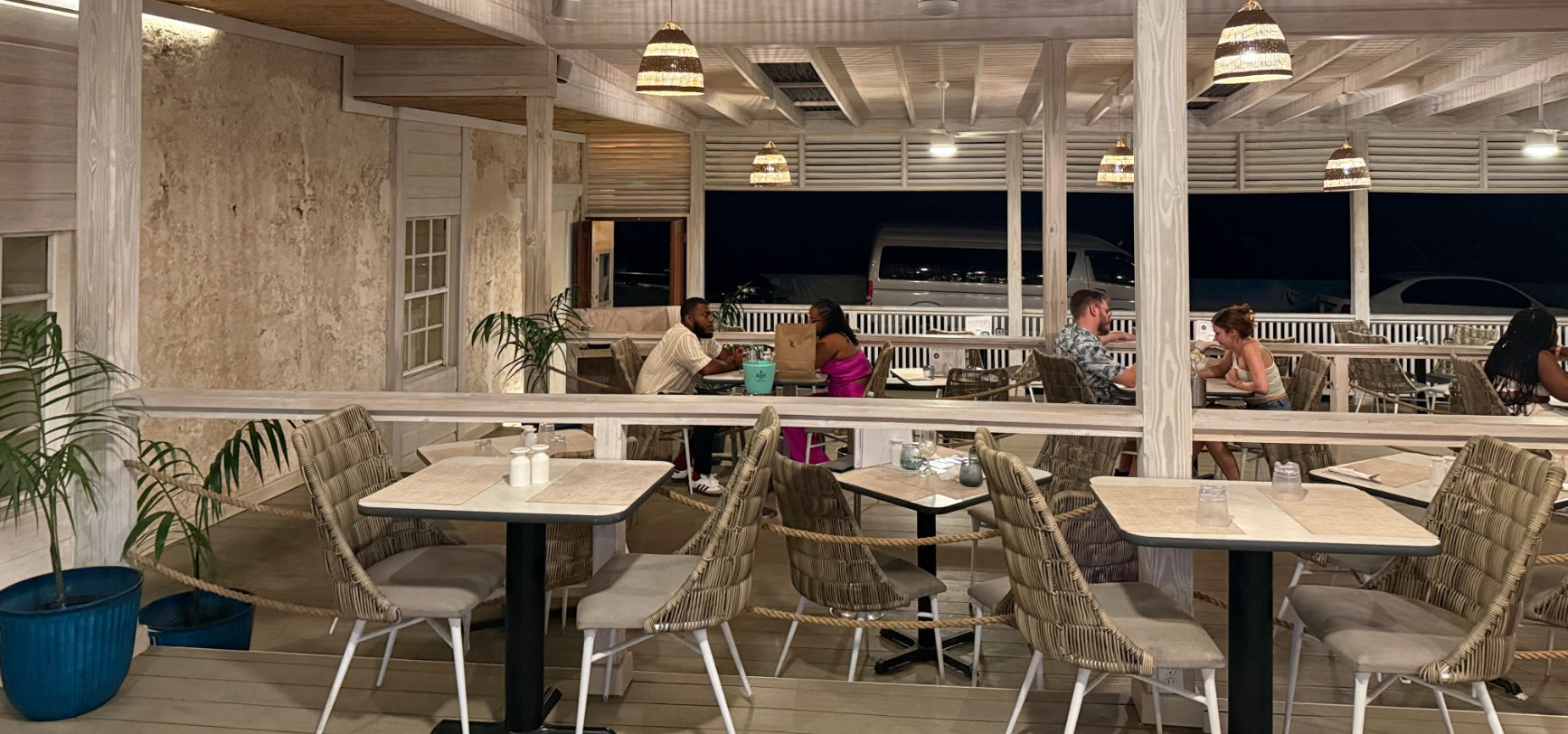 Diners on a quiet evening with the open sides onto the night and cars parked on the road by the sea