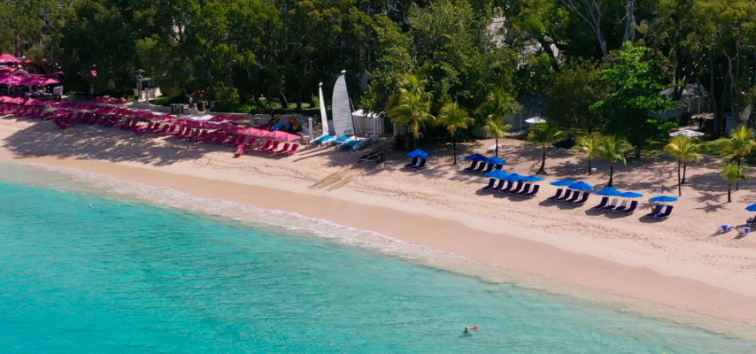 Aerial view of Sandy Lane Bay, Barbados, with the hotel's signature pink loungers and the Estate Beach Club's blue ones alongside
