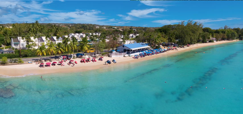 The white sand and turquoise water of Mullins Bay on the west coast of Barbados, with loungers and a beach restaurant behind