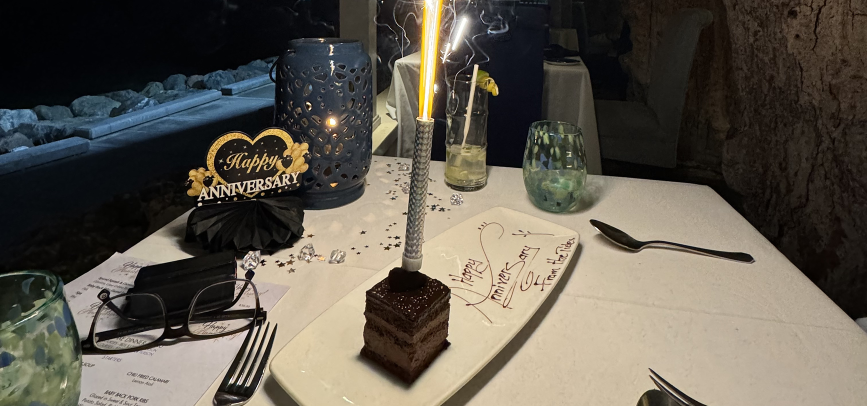 A chocolate dessert with a lit sparkler at The Tides, the plate written Happy Anniversary