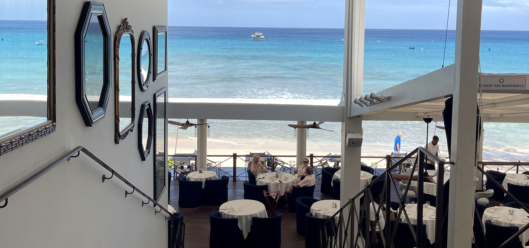 The staircase down into the beachfront dining room at The Lone Star, with the sand and sea beyond