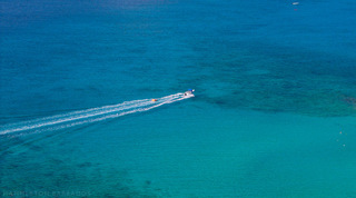 Speedboat towing an inflatable ride across the turquoise Caribbean Sea not far from Queens Fort Pavilion, Barbados