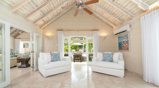Pair of white armchairs framing open French doors to the covered terrace at Queens Fort Pavilion villa, Barbados