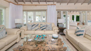 Cream leather sofas around a root-base coffee table with doors to the terrace at Queens Fort Pavilion, Barbados