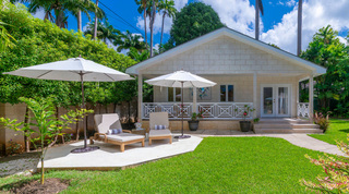 Wooden sun loungers and parasols in front of a stone cottage with a fretwork veranda, Queens Fort Pavilion, Barbados