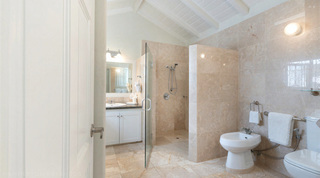 En-suite with a glass-door walk-in shower and white vanity under a vaulted ceiling at Queens Fort Pavilion villa in Barbados