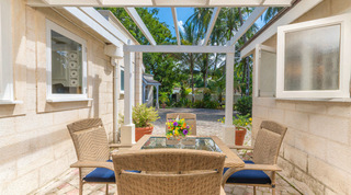 Courtyard dining set with navy cushions under a white pergola between the wings of Queens Fort Pavilion in Barbados