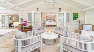 Rope-back armchairs and orchids on a covered terrace opening into a four-poster bedroom at Queens Fort Pavilion in Barbados
