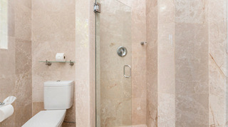 Corner shower with a glass door next to the WC and a glass shelf at Queens Fort Pavilion, Barbados