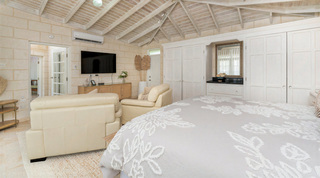 Pair of cream leather armchairs facing a wall-mounted TV in a bedroom suite at Queens Fort Pavilion, Barbados