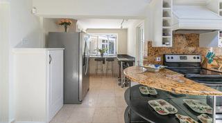 Kitchen with a stainless steel fridge, curved breakfast counter and window bar stools at Queens Fort Pavilion, Barbados
