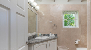 Single-basin vanity under shell-shaped lights beside a scroll-grilled window onto palms, Queens Fort Pavilion, Barbados