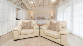 Bedroom suite with cream leather armchairs and built-in wardrobes at Queens Fort Pavilion, a private villa in Barbados