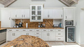 Fully equipped kitchen with a glass-fronted china cabinet and wine fridge at Queens Fort Pavilion villa rental, Barbados