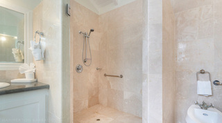 Glass-door walk-in shower with a grab bar and handheld spray beside the bidet at Queens Fort Pavilion villa, Barbados