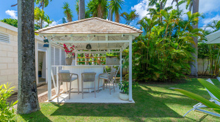 Queens Fort Pavilion's poolside bar with rope-back stools and open shelving under a shingled gazebo roof, Barbados
