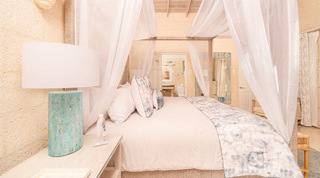 Sheer-draped canopy bed and turquoise mosaic lamp with the en-suite beyond, Queens Fort Pavilion, Barbados