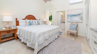 Bedroom with an arched cane headboard, angelfish cushions and coastal artwork at Queens Fort Pavilion in Barbados