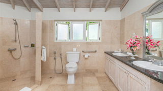 Bathroom with an open walk-in shower and pink lilies on the twin vanity at Queens Fort Pavilion in Barbados