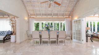 Long dining table before folding glass doors onto the tropical garden at Queens Fort Pavilion, Barbados