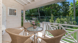 Wicker chairs around a glass-topped table on a fretwork-railed veranda at Queens Fort Pavilion, a villa rental in Barbados