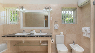 Twin-basin vanity with a glass shelf beside the WC and bidet in an en-suite at Queens Fort Pavilion villa, Barbados