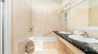 Tiled bath with a woven basket beside a twin-basin vanity at Queens Fort Pavilion, Barbados