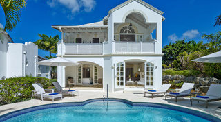 Private curved pool and sun loungers below the white facade of Royal Villa 1 – Swansway, luxury villa in Barbados