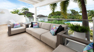 Covered terrace sofa overlooking the resort pool at Royal Villa 17, a holiday villa in Barbados