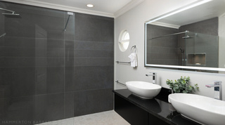 Grey tiled walk-in shower and a black granite vanity in an en-suite at Royal Villa 17, Barbados