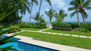 Communal lap pool at Smugglers Cove 1 in Barbados, lawn and stepping stones running to the sea