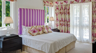 Guest bedroom with a striped headboard and floral drapes, Smugglers Cove 1, apartments in Barbados