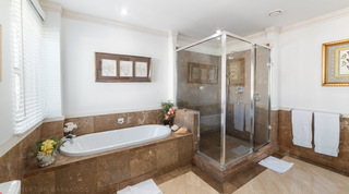 Smugglers Cove 3 bathroom with a built-in bath beneath white coral prints beside a glass corner shower, St. James, Barbados