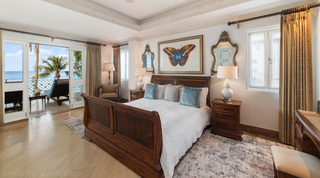 Butterfly print between gold-framed mirrors over the sleigh bed, sea beyond the terrace doors, Smugglers Cove 3 in Barbados