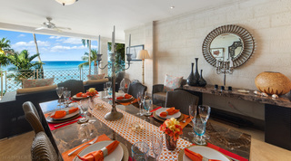 Alfresco dining table with orange napkins, a candelabra and sea views at Smugglers Cove 3 in Paynes Bay, Barbados