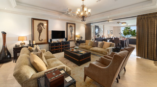 Living room with plush gold sofas and seahorse prints either side of the TV at Smugglers Cove 3, apartment in Barbados