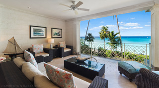 Sea-view covered terrace with wicker seating and a model yacht, Smugglers Cove 3 luxury apartment, Barbados