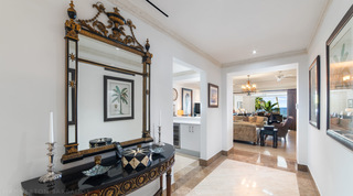 Entrance hall with a black and gold mirror over a demilune console, living room and sea beyond, Smugglers Cove 3 in Barbados